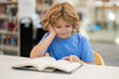 © Volodymyr - Kid reading book. Child reading book in school library. Learning from books. School education. Back to school Child reading book in a public library.
