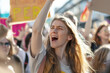 © Bonsales - Young woman passionately protesting in a crowd, raising her arm and shouting with determination. Surrounded by people holding signs, advocating for a cause