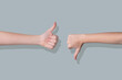 © Kufotos - Two hands showing thumbs up and thumbs down gestures on a gray background.