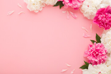 Wall Mural - Fresh beautiful soft white pink peony flowers with green leaves on pink table background. Pastel color. Closeup. Empty place for inspirational text, lovely quote or positive sayings. Top down view.