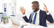 © Prostock-studio - Excited african american businessman expressing joy and happiness in office, got new clients, looking at laptop, free space