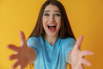 Wall Mural - Screaming of shock or anticipation, hands gesture. Young woman is against yellow background