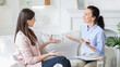 © Prostock-studio - Two women are seated on a comfortable white sofa having an engaging conversation. One woman appears to be a therapist holding a clipboard, while the other, dressed casually, seems to be the client.