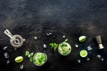 Poster - Mojito cocktail. Summer cold drink with lime, fresh mint, and ice. Cool beverage on a black background, shot from the top with copy space