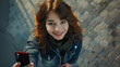 © Alina Tymofieieva - Top view of a happy woman with a phone in her hands. A young woman takes a selfie with her phone outdoors. Technology concept.
