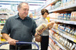© caftor - Mature man carefully reads date of packaging of rice in the grocery section of supermarket