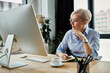 © LIGHTFIELD STUDIOS - A middle-aged businesswoman with short hair focuses intently on her computer screen at her office desk.