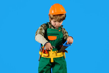 Wall Mural - Little boy in hard hat and builder's uniform with tool belt. Little child playing builder, carpenter or repairman with toy construction tools. Adorable kid in safety helmet and overalls with toolbelt.