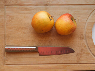 Two Red apple and knife resting on a cutting board