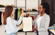 © Prostock-studio - Two multiracial women are browsing through racks of clothes in a busy clothing store. They are holding clothing items and discussing their choices
