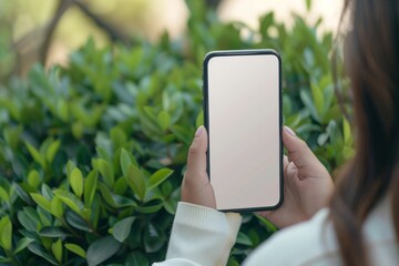 A woman sits in the top view holding a mock-up smartphone with a blank screen