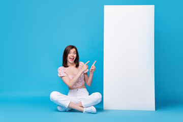 Sticker - Photo of excited funny lady sit hand direct big telephone demonstrate booking service app empty space isolated on blue color background