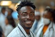 © Denis - smiling afro doctor with colleagues in background, looking at camera
