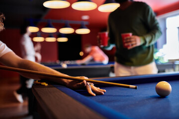 Wall Mural - A close-up shot of a man playing billiards with friends in a casual setting.