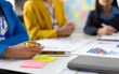 © Wasan - Businesswoman working on documents with colleagues in business consulting meeting and discussing business project.