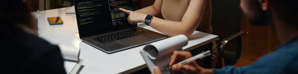 Header with developer showing code on laptop screen in meeting