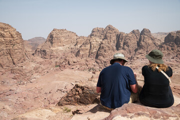 Petra, paisaje panoramico con dos turistas descansando mirando la ciudad, Jordania.