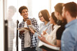 © Prostock-studio - Students writing tasks on whiteboard in class, laughing with classmates