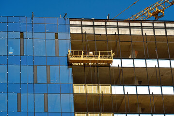 Poster - Suspended platform, insulation facade walls. Detailed view of installation of glass curtain wall. Lifting platform and structural glass wall installation. Suspended cradle for cladding wall