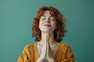 Canvas Print - Portrait of a blissful caucasian woman in her 30s joining palms in a gesture of gratitude while standing against pastel green background