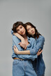 © Bliss - A stylish lesbian couple, both wearing denim, pose against a grey backdrop.