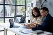© Wasana - A man and a woman are sitting at a desk looking at a computer screen