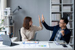 © Wasana - Two people are high fiving each other in a business setting