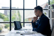 © Wasana - A man in a suit is sitting at a desk with a laptop and a tablet