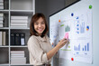 © Wasana - A woman is standing in front of a whiteboard with a smile on her face