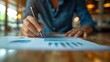 © Naret - Person working on business analysis report with graphs and charts at a wooden table, using a pen in a cozy cafe setting.