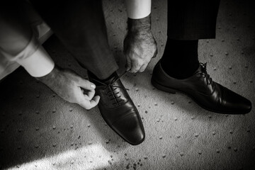 A close-up shot of a man tying his formal shoes, highlighting the detail and craftsmanship of the footwear.