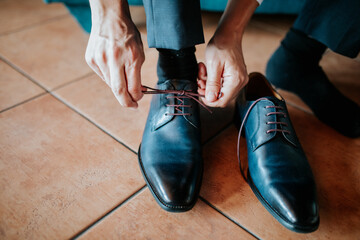 A close-up shot of a man tying his formal shoes, highlighting the detail and craftsmanship of the footwear.