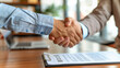 © Taskmanager - Close-up of two people shaking hands over a contract in a business setting, symbolizing successful negotiation, agreement, and partnership in a professional environment.