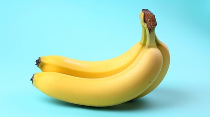 Wall Mural - Three ripe yellow bananas isolated on a blue background. The bananas are slightly curved and have brown stem ends.