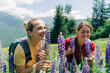 © Ilona - Two women walk in a mountain meadow and smell wildflowers.