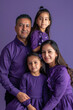 © wolfhound911 - a Hispanic family in coordinated purple outfits, looking serious while posing together on a purple studio background
