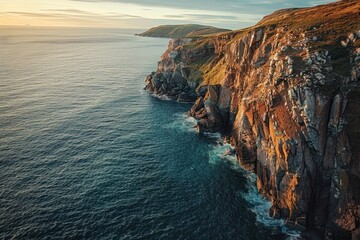 Wall Mural - An aerial photo at sunrise of a rugged coastal cliff, showcasing its dramatic beauty with golden sunlight illuminating the cliffs and ocean below