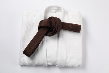 Brown karate belt and kimono on white background, top view