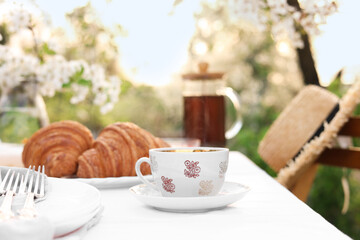 Canvas Print - Stylish table setting with tea and croissants in spring garden