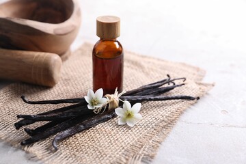 Wall Mural - Vanilla pods, essential oil and flowers on light gray table