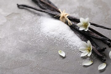 Wall Mural - Vanilla pods, sugar, flowers and petals on gray textured table, closeup. Space for text