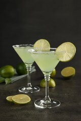 Wall Mural - Delicious Margarita cocktail in glasses and limes on grey table