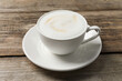© New Africa - Tasty cappuccino in coffee cup on wooden table, closeup