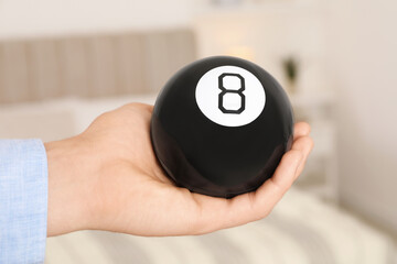 Wall Mural - Man holding magic eight ball indoors, closeup