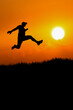© STOCK PHOTO 4 U - Silhouette of Person Jumping Against a Vibrant Orange Sunset Sky with Glowing Sun