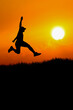 © STOCK PHOTO 4 U - Silhouette of Person Jumping Against Vibrant Orange Sunset Sky in Open Field