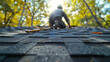 © SashaMagic - Worker repairing roof shingles on a sunny autumn day.