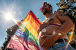 © Виктория Котлярчук - Happy future pregnant transgender man holding his stomach during pride month. Rainbow flag and sun