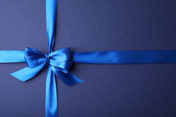 Wall Mural - Bright satin ribbon with bow on blue background, top view