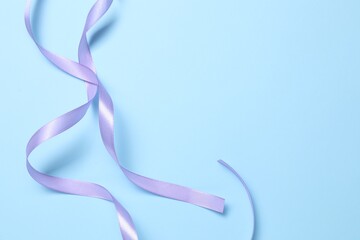 Wall Mural - Beautiful violet ribbon on light blue background, top view. Space for text
